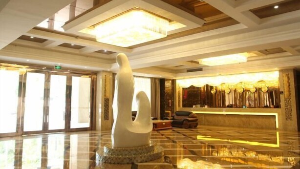 A lobby with a large white sculpture, a reception desk, and a chandelier. - Xin Haiyi Hotel (Kaiping)