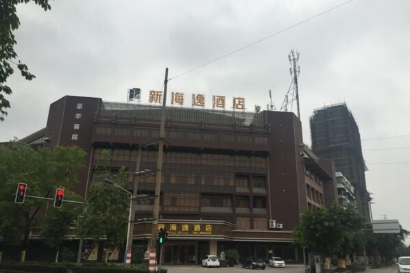 A hotel with a prominent sign, multiple floors, and a parking area. - Xin Haiyi Hotel (Kaiping)
