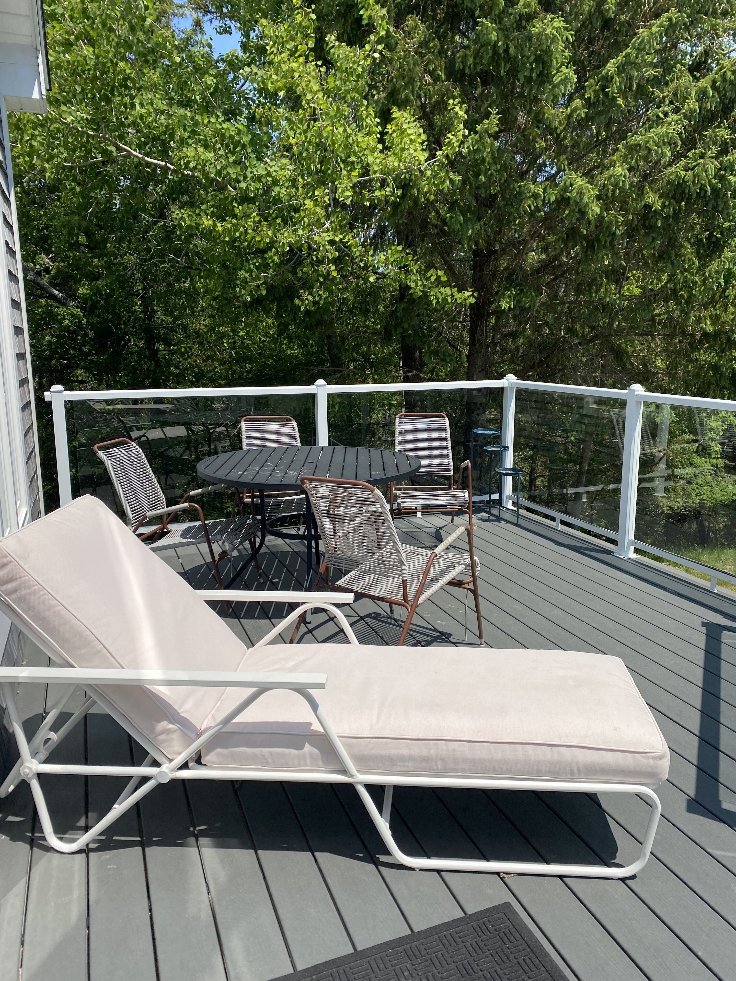A deck with a table and chairs, surrounded by a white railing.