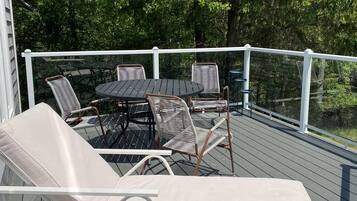 A deck with a table and chairs, surrounded by a white railing.