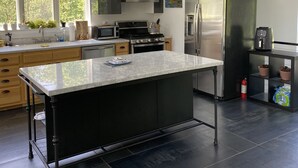 A modern kitchen with a central island, built-in appliances, and large windows.