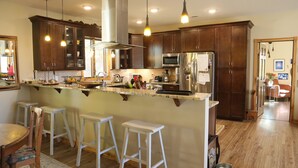 Een moderne keuken met houten kasten, een roestvrijstalen koelkast en een centraal eiland met barstoelen.