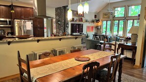 Een ruime keuken met houten kastjes, een groot eiland en een eetgedeelte met een houten tafel en stoelen.