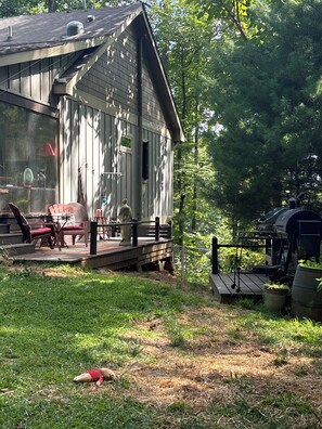 Eine Holzhütte mit einer Terrasse, Sitzgelegenheiten im Freien und einem Grill.