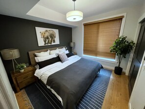 Bedroom with a King bed, an alarm clock, charging outlets, and an extra blanket.