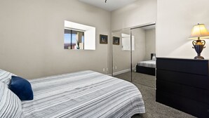 Une chambre à coucher avec un lit, une commode, un miroir et une fenêtre.