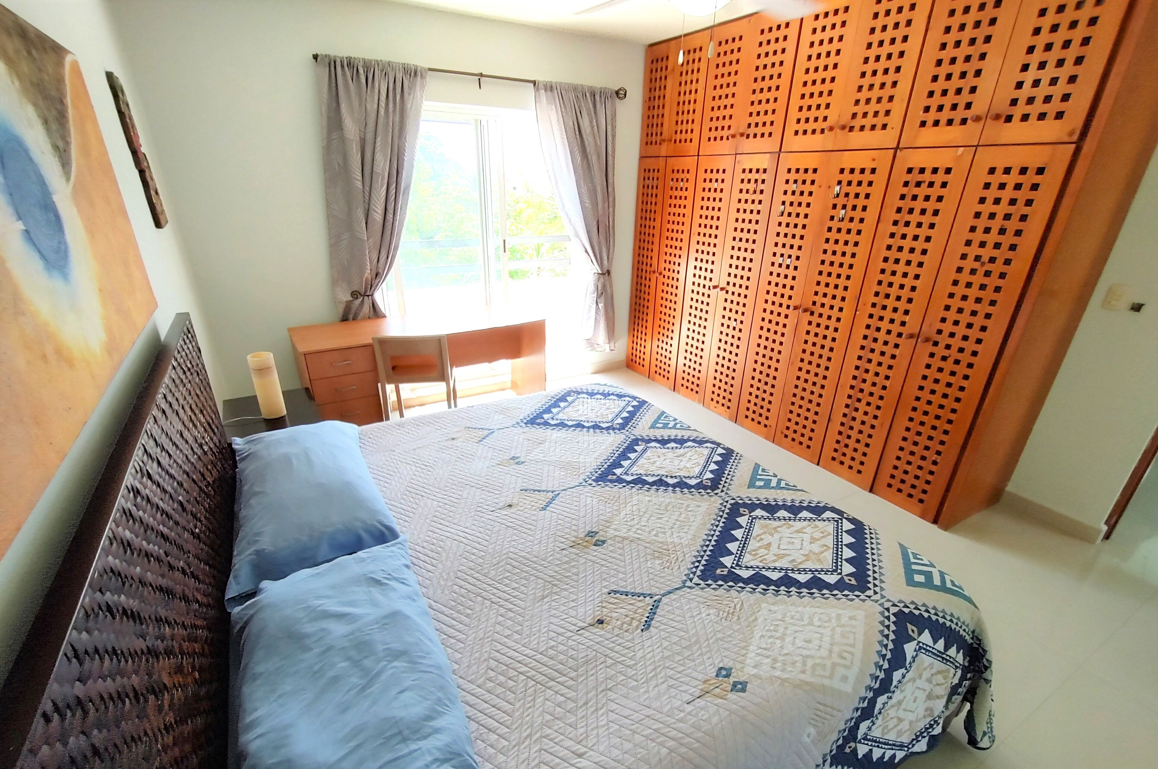 A bedroom with a bed, a desk, and a wardrobe.