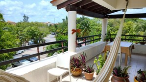 Un balcon privé avec un hamac, des plantes en pot, une table et des chaises.