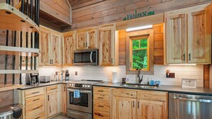 Une cuisine moderne avec des meubles en bois, des appareils en acier inoxydable et une fenêtre donnant sur un paysage verdoyant.