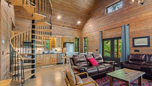 Un intérieur en bois avec un escalier en colimaçon, des meubles en cuir et un coin cuisine.