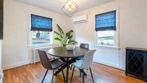 Un comedor con una mesa redonda, cuatro sillas, una planta en maceta y un mueble negro.