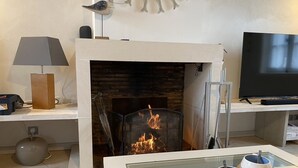 Una sala de estar con chimenea, televisor de pantalla plana y una mesa de centro con tazas.