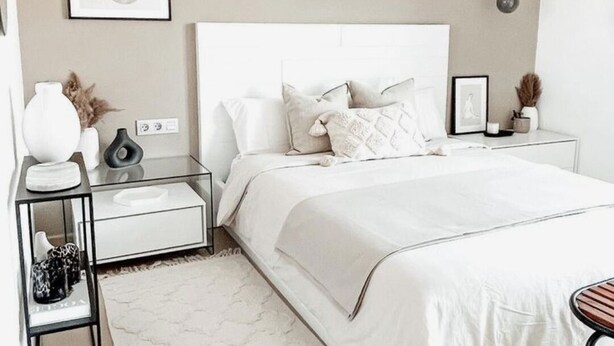 A modern bedroom with a white bed, a bedside table, a nightstand, and a wall-mounted light fixture. - Beautiful sea view apartment (Azeffoun)