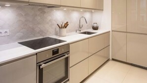 A modern kitchen with a sleek design, featuring a large island with a sink, a built-in oven, and ample counter space. - Beautiful sea view apartment (Azeffoun)