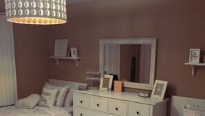 A bedroom with two beds, a dresser, a mirror, and a hanging light fixture. - Beautiful sea view apartment (Azeffoun)