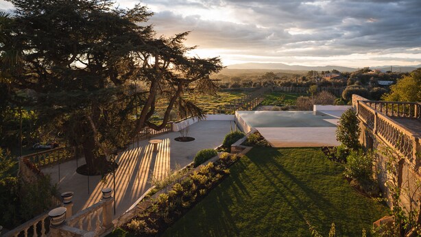 Terraza en la azotea con vistas a un viñedo y colinas lejanas bajo un cielo nublado.