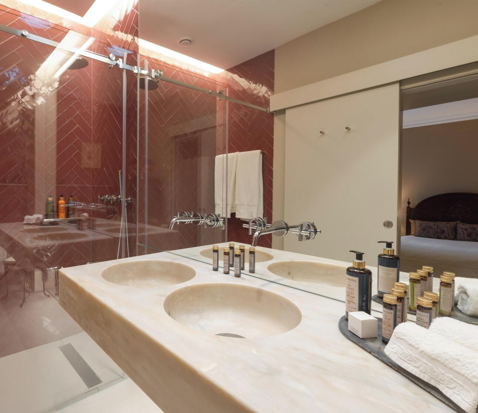 Une salle de bain moderne avec deux lavabos, un grand miroir et une douche.