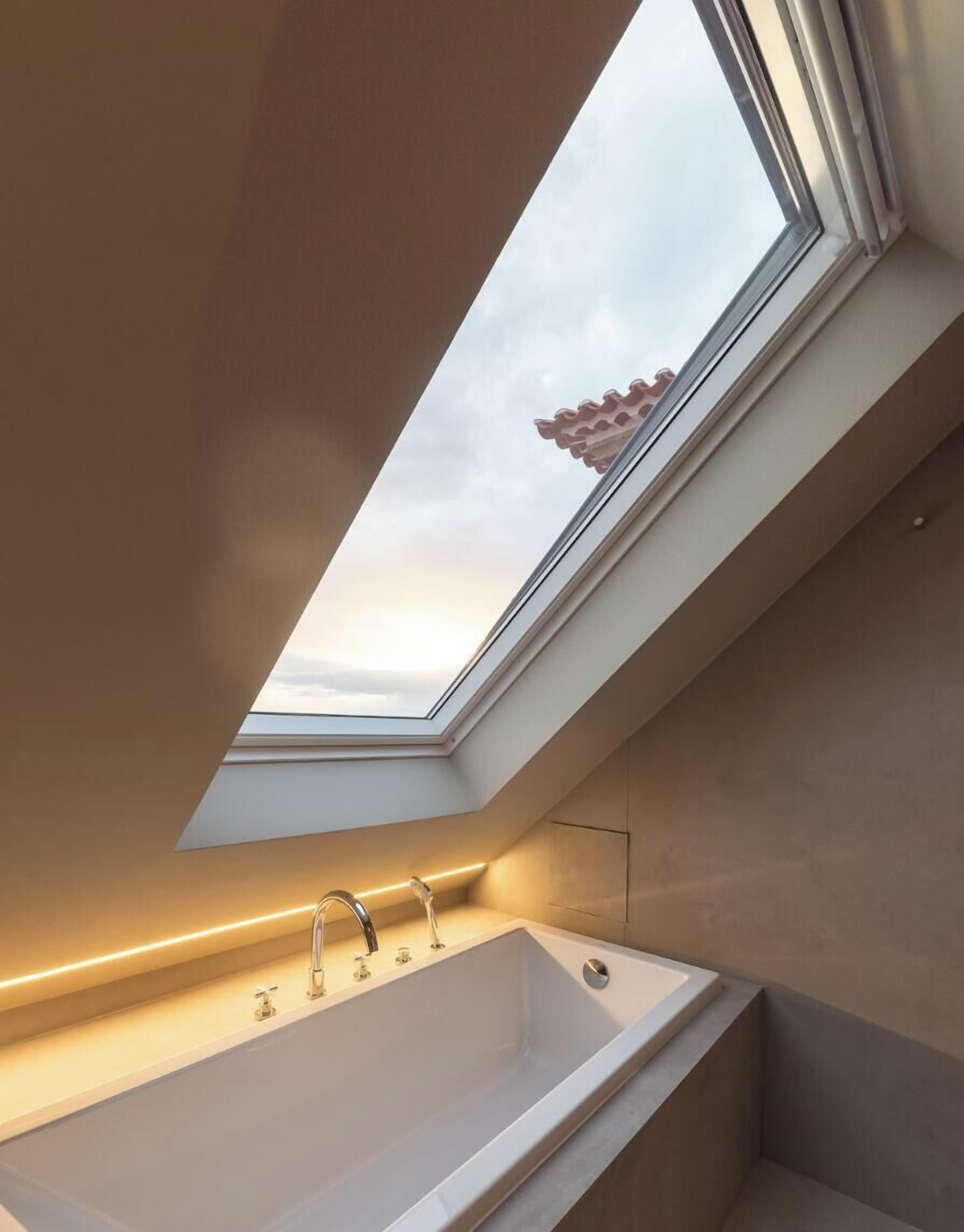 A skylight above a modern bathroom with a bathtub and two faucets.