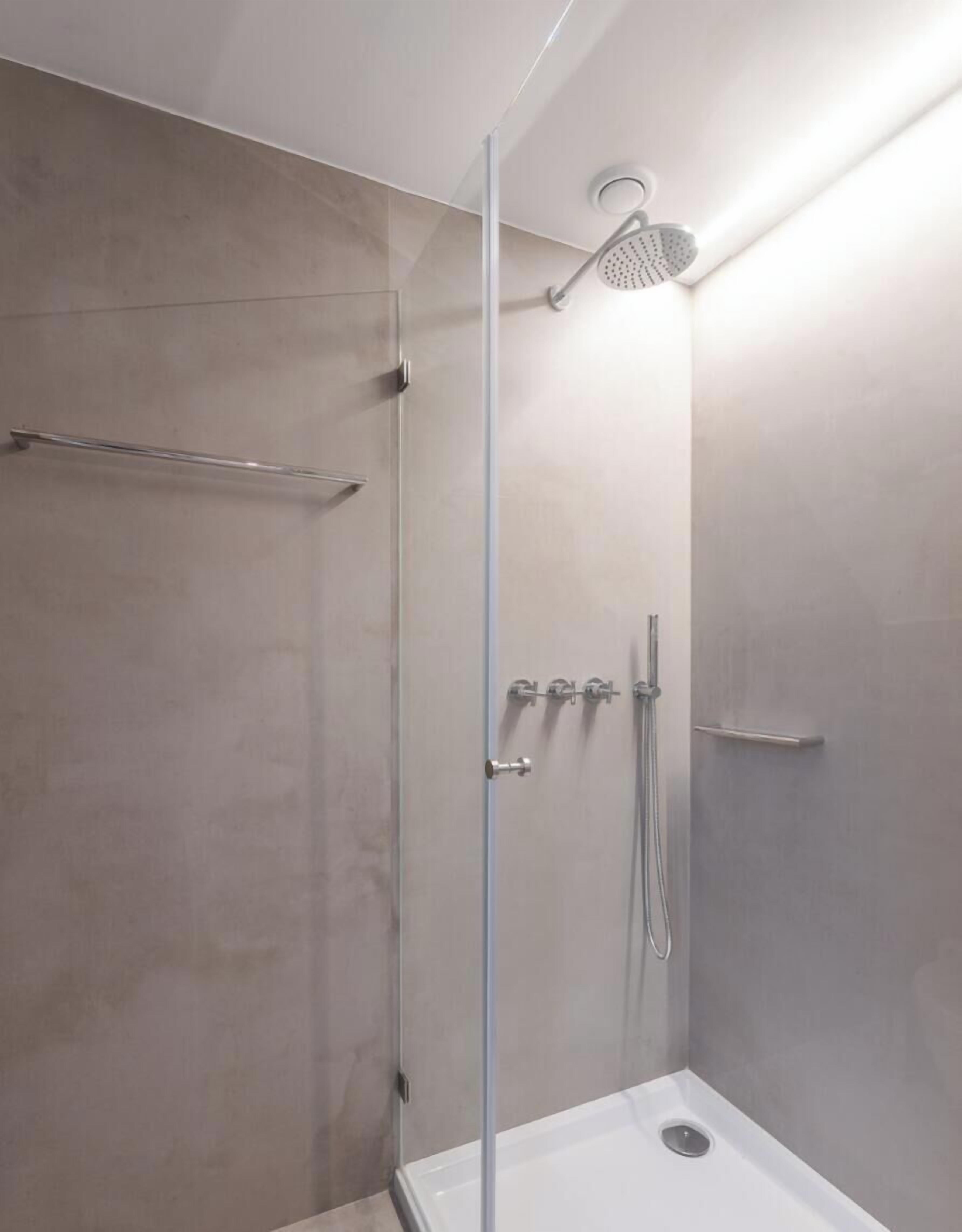 A modern shower with a glass door, a handheld showerhead, and a handheld shower attachment.