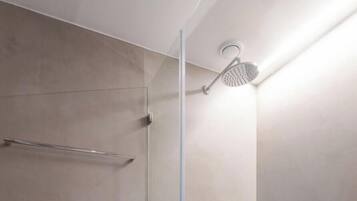 A modern shower with a glass door, a handheld showerhead, and a handheld shower attachment.