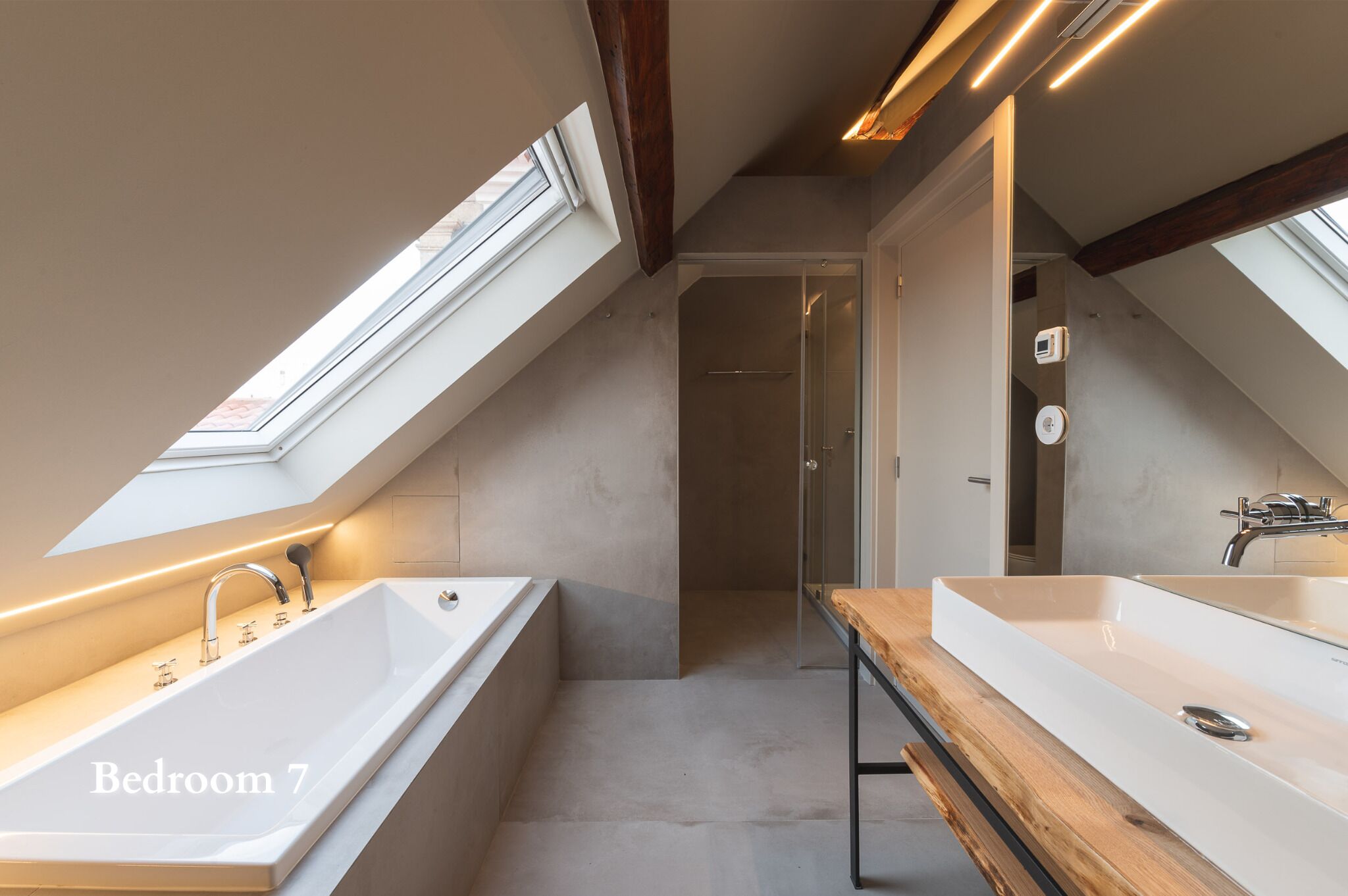 Ein modernes Badezimmer mit Oberlichtern, einer großen Badewanne und einem Doppelwaschbecken.