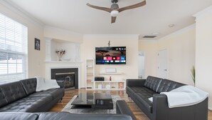 Ein modernes Wohnzimmer mit zwei schwarzen Ledersofas, einem Glastisch und einem flachbildfernseher, der an der Wand montiert ist.