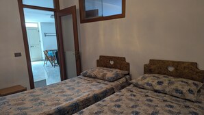 Ein Schlafzimmer mit zwei Einzelbetten, jeweils mit einem Holzfußende und floralem Bettbezug.