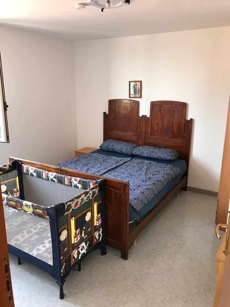Una cama individual con cabecera de madera y colcha azul estampada.