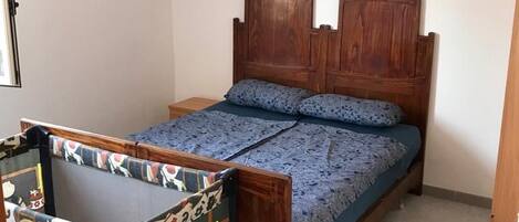 Una cama individual con cabecera de madera y colcha azul estampada.