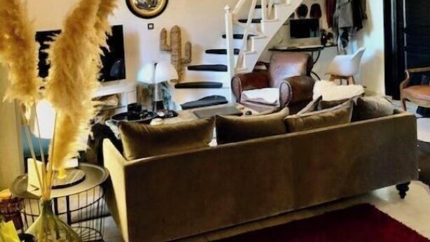 A living room with a sofa, a red rug, and a staircase. - House in former wine estate (BEZIERS)