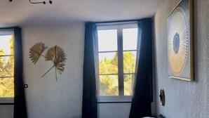 A bedroom with a bed, two windows, and wall decorations. - House in former wine estate (BEZIERS)