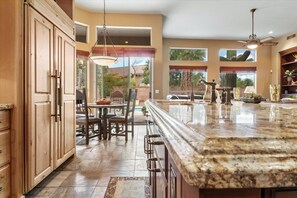 Enjoy meals in the kitchen with a large island, sink, and bar stools, surrounded by windows offering a view of the outdoors.