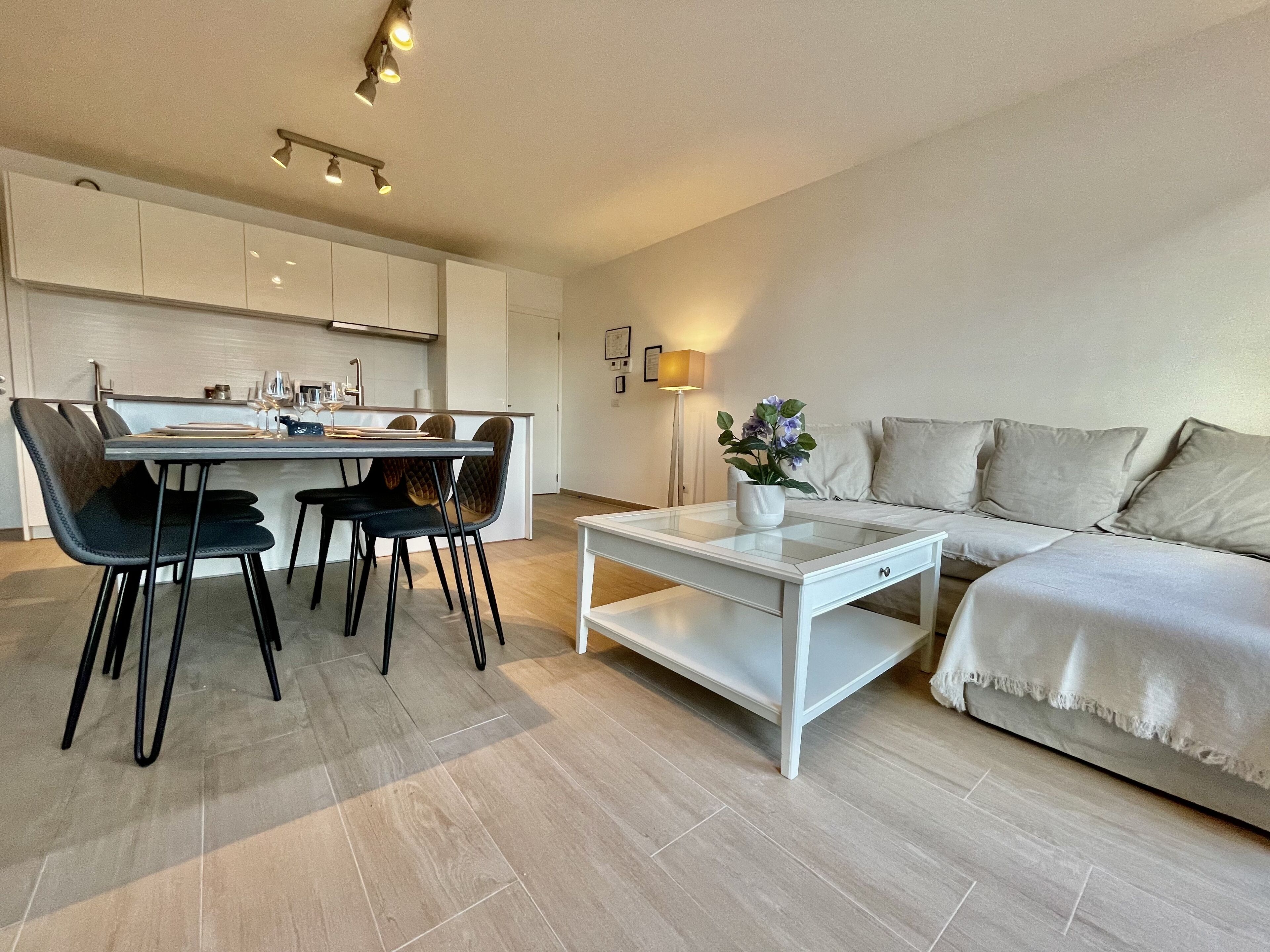 Una sala de estar moderna con una mesa de centro de vidrio, un sofá y un comedor con sillas y una mesa.