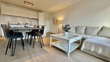 Una sala de estar moderna con una mesa de centro de vidrio, un sofá y un comedor con sillas y una mesa.