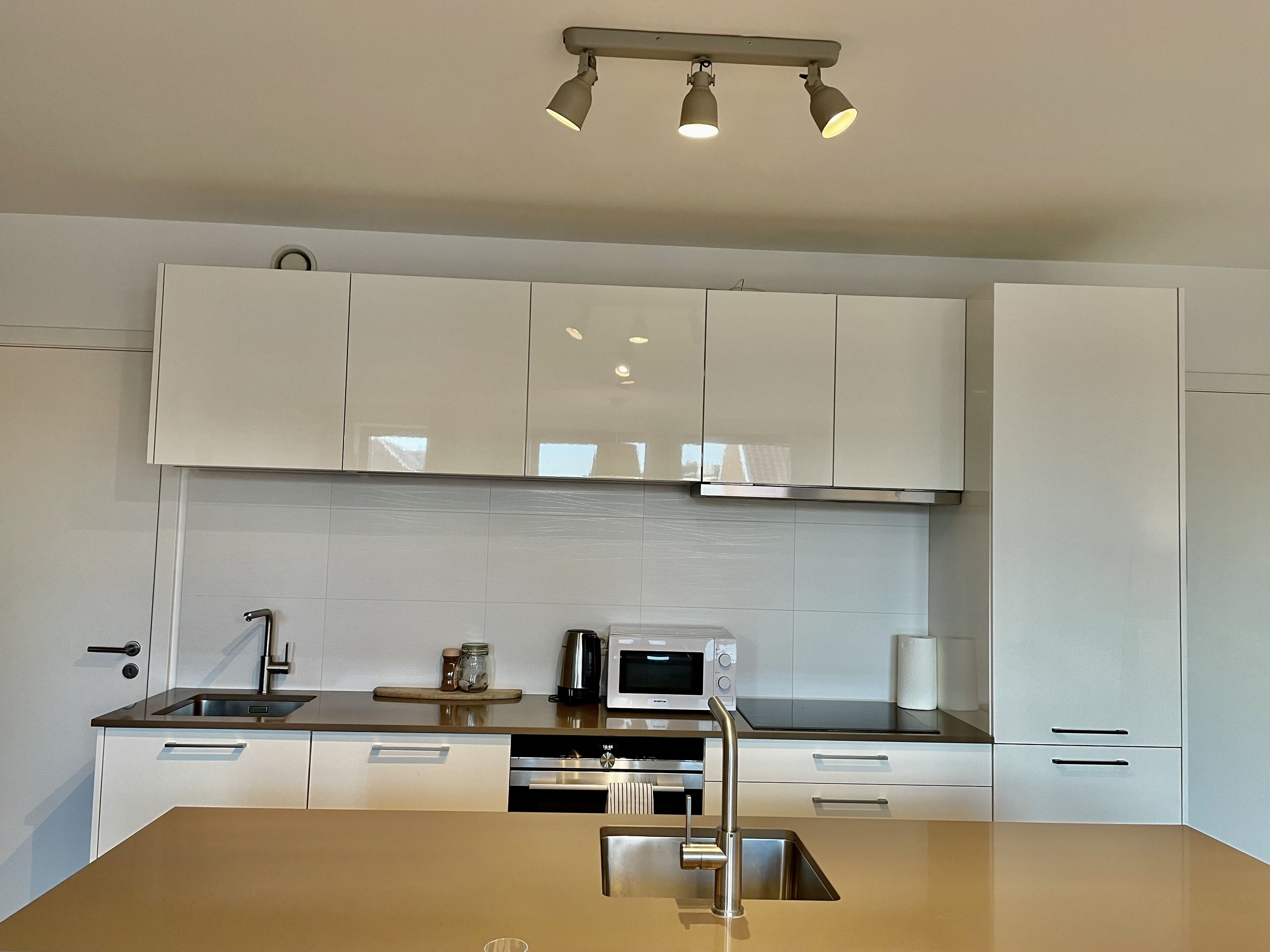 Una cocina moderna con armarios blancos, electrodomésticos de acero inoxidable y una isla central.