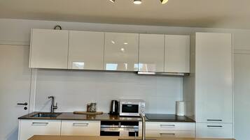 Una cocina moderna con armarios blancos, electrodomésticos de acero inoxidable y una isla central.