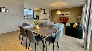 Un salon moderne comprenant un coin repas, une cuisine et un téléviseur.