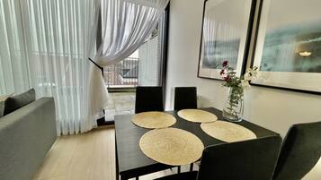 A modern dining area with a dark wooden table, black chairs, and woven placemats.