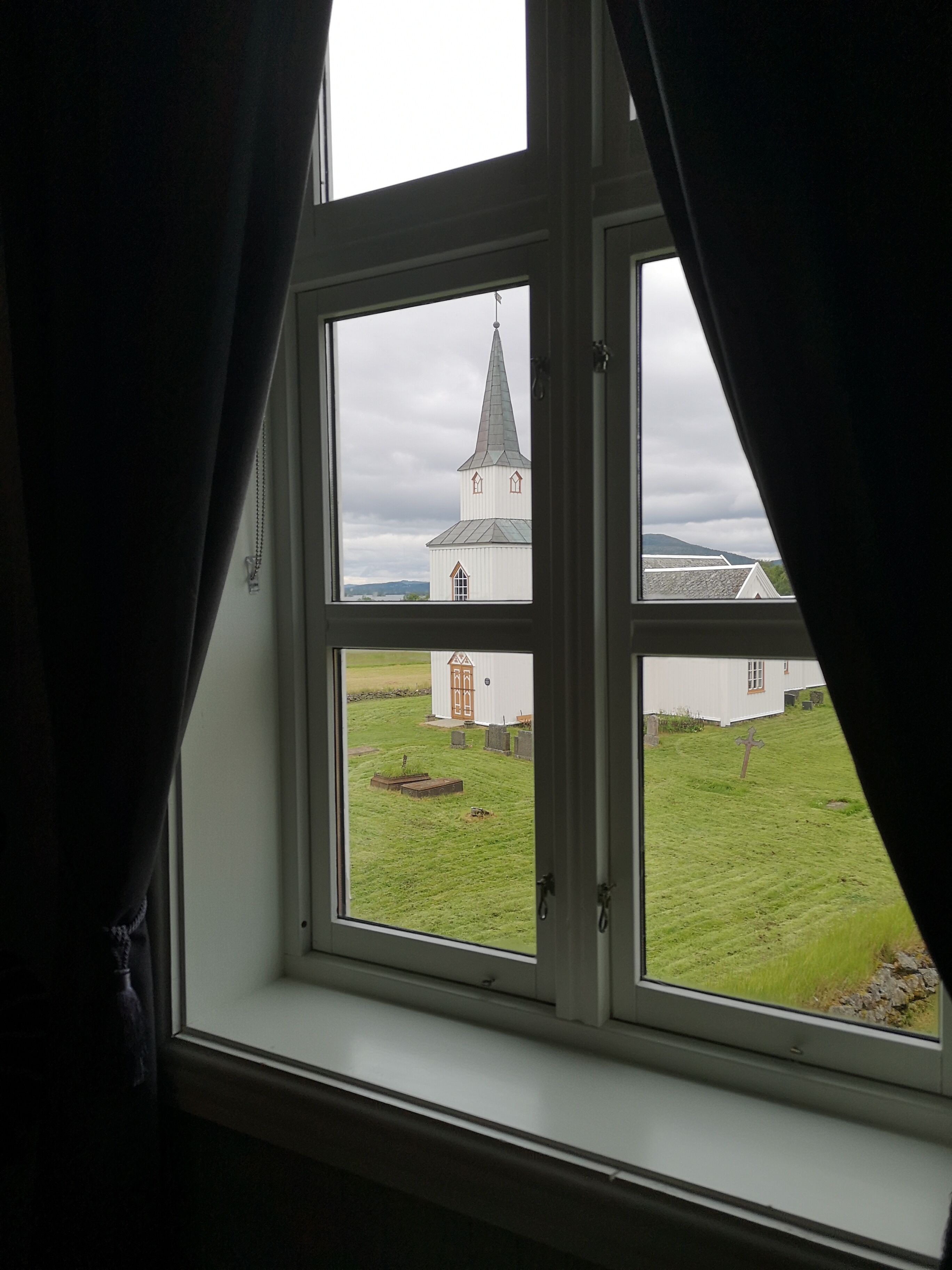 Una ventana con vista a una iglesia y un cementerio.