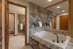 Bathroom features a large bathtub and a spacious mirror.