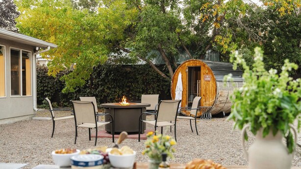 An outdoor patio with a fire pit, seating, and a rustic barrel.