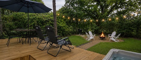 Eine Terrasse im Freien mit Whirlpool, Tisch und Stühlen sowie Lichterketten.