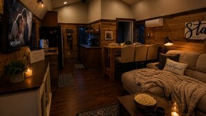 Ein gemütliches Zimmer mit einer Couch, einer Essecke, einer Küche und einem an der Wand befestigten Fernseher.
