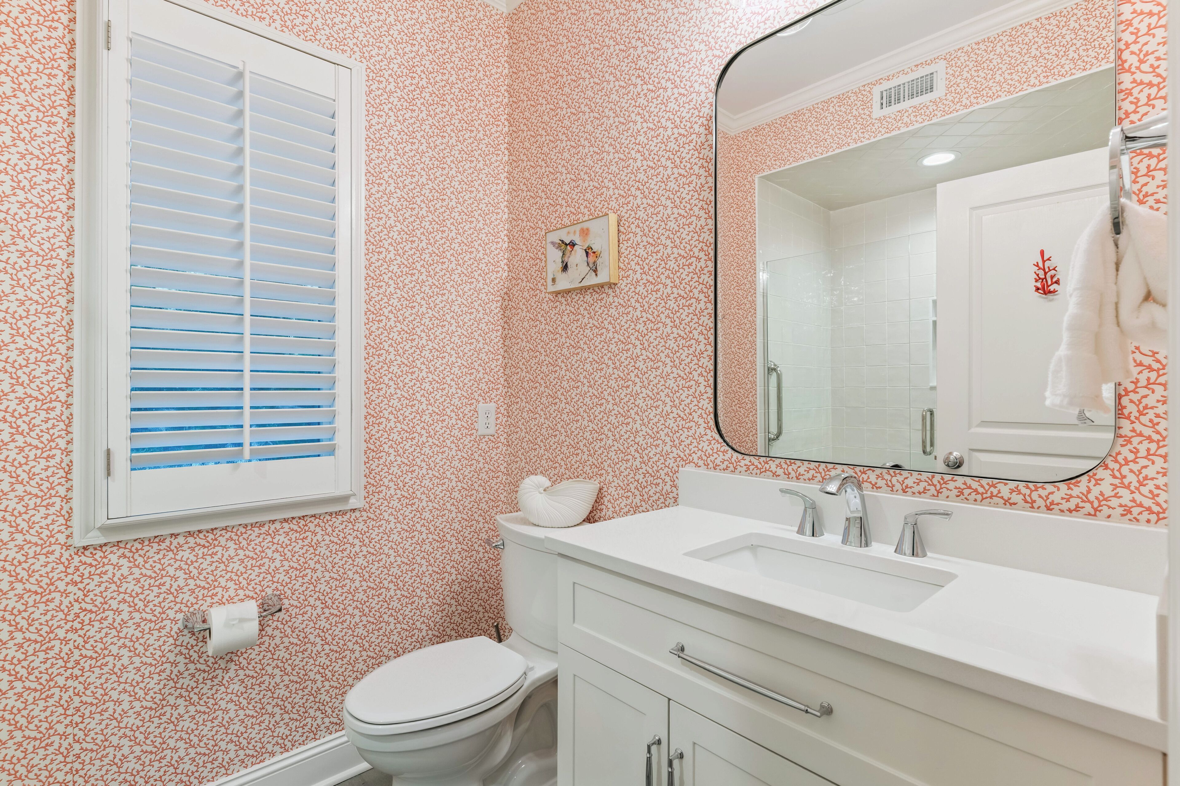 A bathroom with a toilet, sink, and mirror.