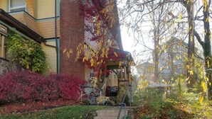 A residential house with a front yard, a staircase leading to the front door, and a garden with various plants and shrubs.