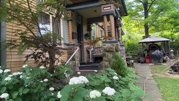 Una casa con porche, columna de piedra y jardín con flores de hortensia.