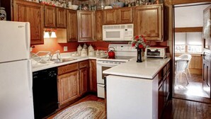 A kitchen with wooden cabinets, a white refrigerator, a microwave, and a stove.