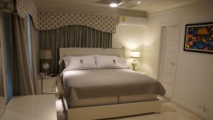 Habitación de hotel ordenada con una cama grande, mesitas de noche, un escritorio y un cuadro en la pared.