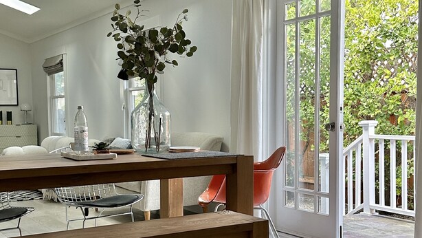 Un comedor moderno con una mesa de madera, sillas y un florero con plantas.