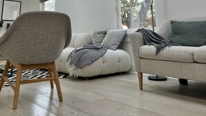 Una sala de estar moderna con techo alto, tragaluces y un ventanal con vistas a zonas verdes.